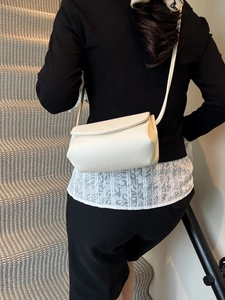Sac bandoulière blanc à motif litchi porté par un mannequin pour un look très élégant