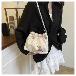 Close-up of embroidered floral pattern and silk drawstring closure on white canvas bag