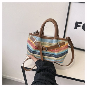 Detail view of woven straw beach bag featuring multi-color stripes and leather handles