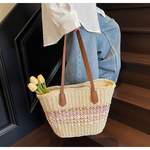 Détail d'un sac cabas en paille avec motifs de losanges roses et anses en cuir brun