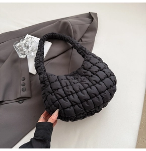 Detail of black pleated cloud bag with quilted texture shown in a minimalist setting