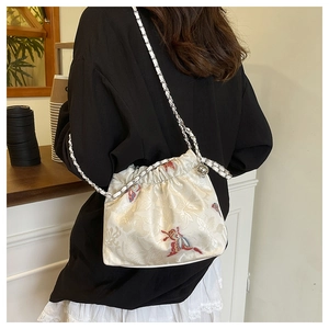 Detail of embroidered butterfly pattern and chain strap on cream canvas bag