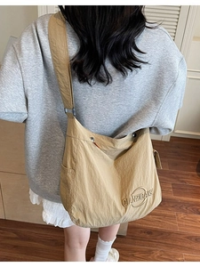 Grande borsa tote minimalista in tela kaki indossata da una modella in un interno