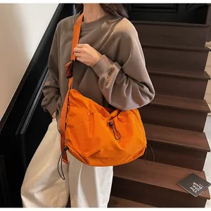 Detail of adjustable strap and drawstring design on orange canvas crossbody bag