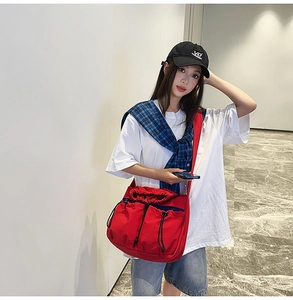 Detail view of red canvas crossbody bag with multi-pocket design and drawstring closure