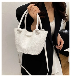 Close-up of white pebble grain handbag showing double knot handle and logo detail
