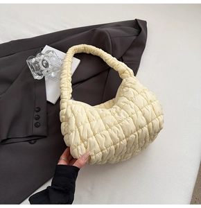 Detailed close-up of yellow quilted puffy shoulder bag texture with zip closure