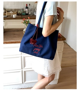 Detail of navy canvas tote bag with red embroidery and matching small hanging charm pouch