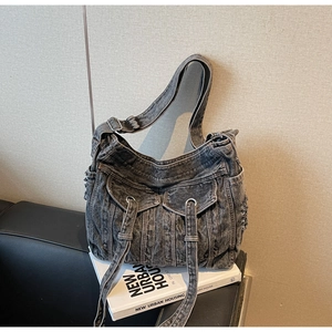 Detail of vintage washed denim tote bag showing dual front flap pockets and metal grommets