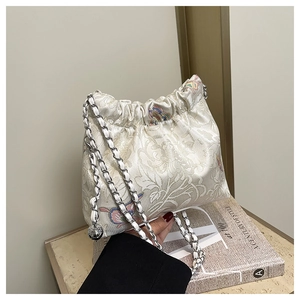Detailed close-up of cream floral jacquard bucket bag with metal chain strap and drawstring