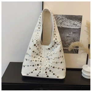 Detail of white leather hobo bag featuring silver rivets and soft texture in a modern room