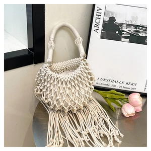 Detailed close-up of bohemian crochet bucket bag with long tassels and gold metal rings