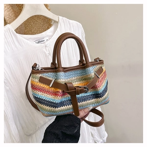 Detail of colorful woven straw bag with brown leather handles and adjustable shoulder strap