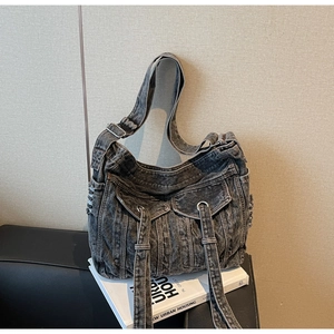 Detailed view of grey washed denim crossbody bag featuring two front cargo pockets and strap