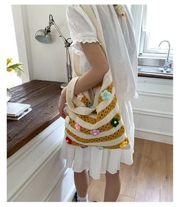 Detail of hand-crocheted striped tote bag with colorful 3D floral accents for women