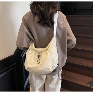 Cream white nylon tote bag with drawstring closure and wide shoulder strap on a model
