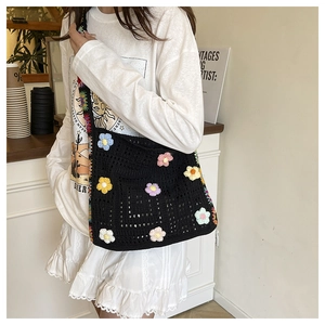 Detail einer schwarzen Häkeltasche mit bunten handgefertigten 3D-Blumenverzierungen