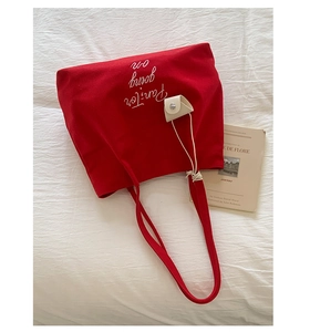 Close-up of red canvas tote bag featuring Pan-Tor text and cream leather charm detail