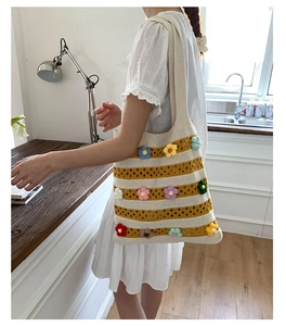 Détail de fleurs 3D tricotées sur un sac cabas rayé en crochet porté par un mannequin
