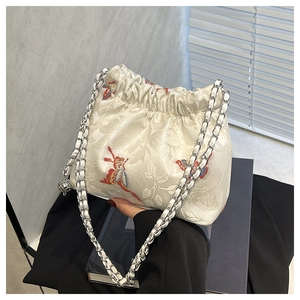 Detail of floral embroidery and butterfly motif on a cream satin drawstring bag