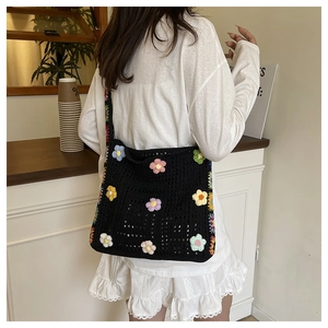 Detailansicht der schwarzen Häkeltasche mit bunten 3D-Strickblumen an der Schulter