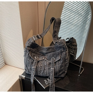 Detail of dark gray washed denim bag featuring cargo pockets and metal hardware accents