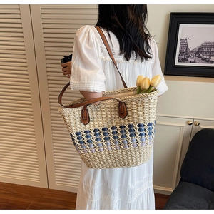 Sac cabas en paille avec motif ajouré coloré et lanières en cuir porté par un mannequin