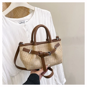 Detail of hand-woven straw tote with brown leather straps and adjustable shoulder belt