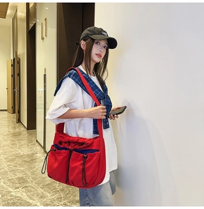 Detailed side view of a large red nylon crossbody bag with unique drawstring pockets
