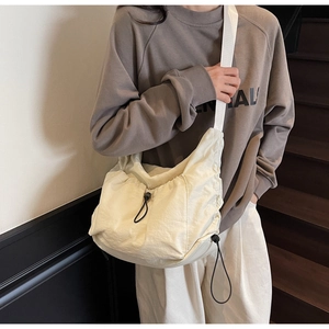 Detail of cream nylon crossbody bag featuring drawstring pleated texture and wide strap