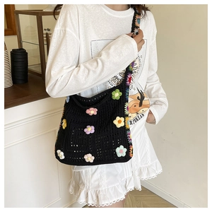 Detail einer handgefertigten schwarzen Häkeltasche mit bunten 3D-Strickblumen-Applikationen