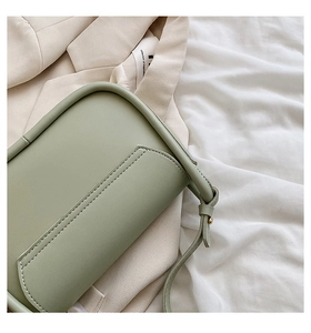 Détail d'un sac selle vert sauge montrant la texture du cuir mat et les coutures fines