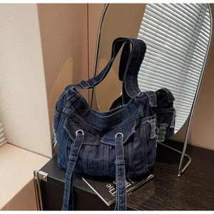 Detail of dark blue denim crossbody bag featuring multi-pocket design and retro frayed edges