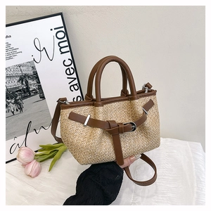 Detail of straw woven tote with brown leather straps and silver buckle for summer beach look