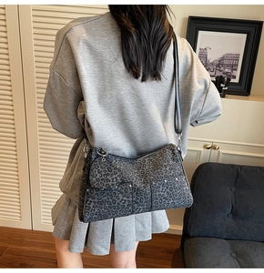 Detail of dark grey leopard print crossbody bag with metal studs and heart charm