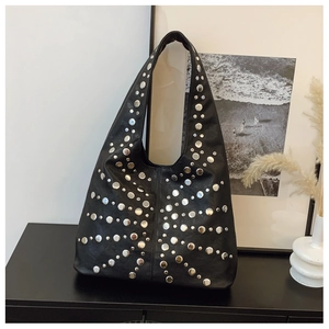 Detail of silver rivets on black leather tote bag with punk style aesthetic
