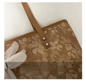 Detail of floral canvas tote bag featuring brown leather handle and 3D fabric flower