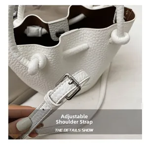Detail of white pebble leather bucket bag with adjustable strap and metal buckle