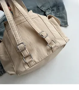 Detail of adjustable metal buckle and stitching on beige nylon canvas backpack