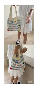 Detail of hand-crocheted striped tote bag with colorful 3D floral accents on white background