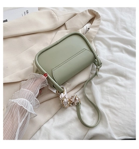 Détail du sac selle vert clair avec foulard en soie et finition en similicuir mat