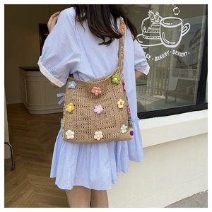Detail der beigen Häkel-Strandtasche mit bunten 3D-Blumen und floralem Schultergurt