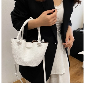 Detail of white lychee leather bucket bag with knotted handle and adjustable strap