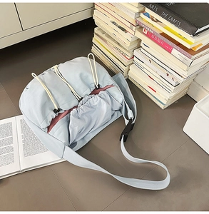 Detailed view of light blue pleated nylon shoulder bag with pink lining and drawstring
