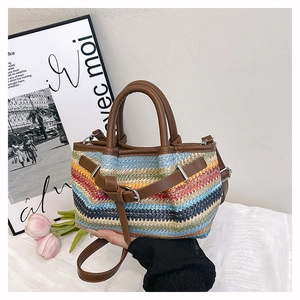 Detail of colorful woven straw bag with dark brown leather straps and silver buckle