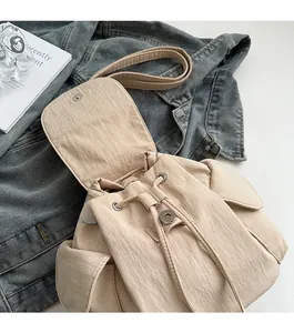 Detail view of the cream drawstring closure and magnetic flap on this canvas backpack