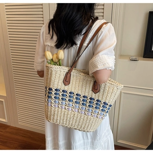 Détail du sac cabas en paille avec motifs géométriques bleus et bandoulières en cuir
