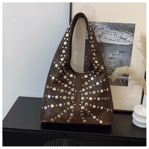 Detail of dark brown Hobo bag with silver studs on a black cabinet in a modern room