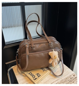 Detail of vintage brown Boston bag with teddy bear charm on marble surface