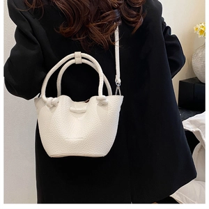 Detailed view of white lychee texture bucket bag with unique knotted handle design